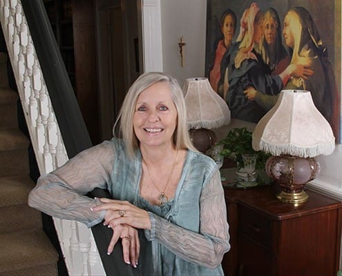 Debbie Mazur, the founder and CEO of GraceWay Recovery Residence for Women in Albany, stands in the home’s foyer. In the background, right, is an image of the Visitation of Mary. The faith-based nonprofit opened its doors in 2003. Photo By Michael Alexander