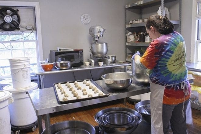 A GraceWay resident works at The Bread House & Granary, an all-natural bakery three miles from the recovery residence. On this particular afternoon she is scooping out oatmeal pecan and oatmeal pecan coconut cookie dough onto a baking tray for 24 cookies. Photo By Michael Alexander