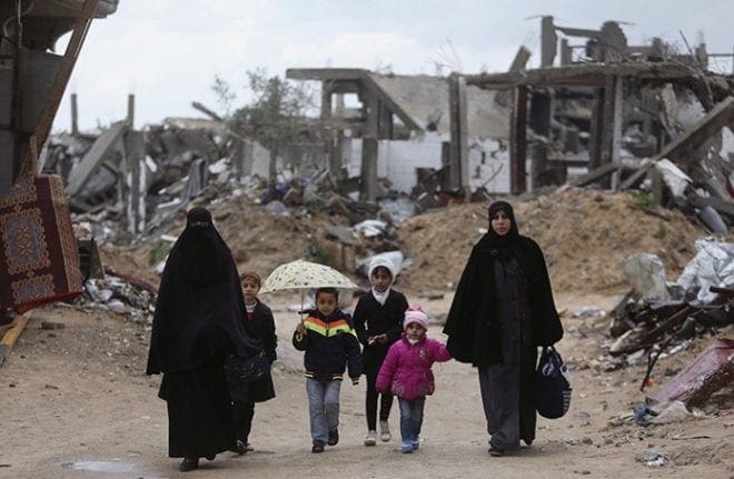 Palestinians walk near the ruins of houses Feb. 20 that witnesses said were destroyed or damaged by Israeli shelling during a 50-day war last summer, near Gaza City. CNS photo/Ibraheem Abu Mustafa, Reuters