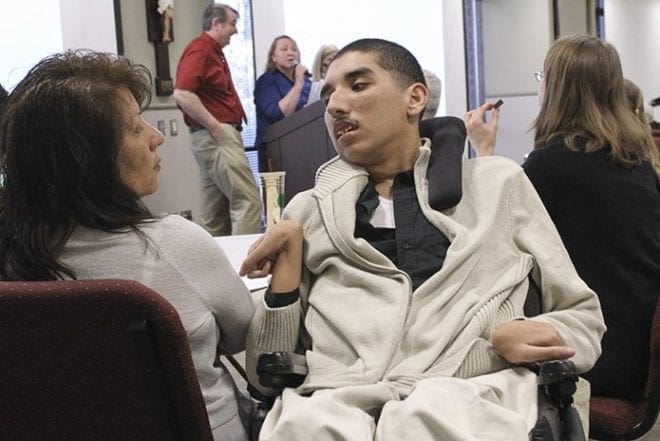 Dina Godoy of St. Michael Church, Gainesville, left, looks over at her 20-year-old disabled son, Jonathan. Godoy’s husband, Juan, also accompanied the family to the conference. Photo By Michael Alexander