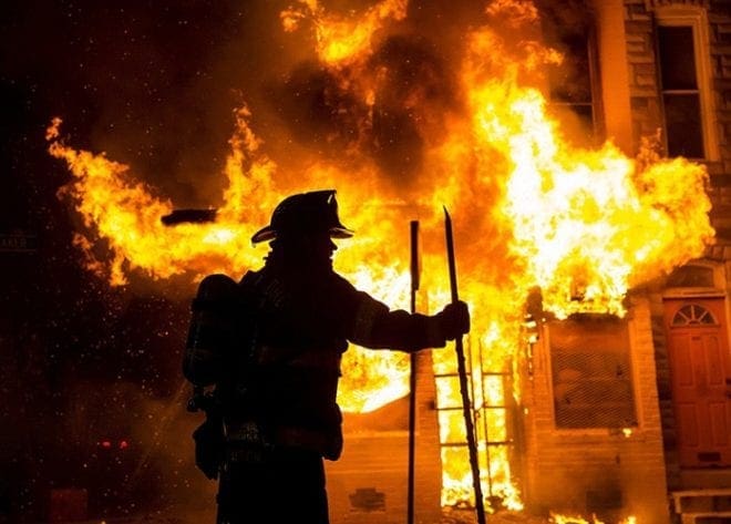 A Baltimore firefighter prepares to attack a fire at a convenience store and residence early April 28 during clashes in response to the unexplained death of Freddie Gray, a 25-year-old black man in police custody in the city. Baltimore erupted in violence as hundreds of rioters looted stores, burned buildings and injured at least 15 police officers following Gray's funeral. CNS photo/Eric Thayer, Reuters