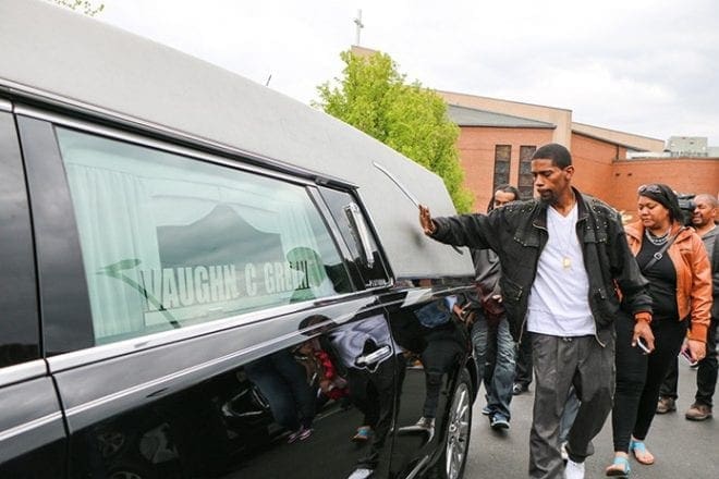 A mourner pats the hearse holding the casket of Freddie Gray outside New Shiloh Baptist Church in West Baltimore April 27 after a funeral service. Riots erupted nearby in response to the death of Gray, 25, who died April 19, one week after being arrested and sustaining a severe spinal cord injury while in police custody. CNS photo/Olivia Obineme, Catholic Review 