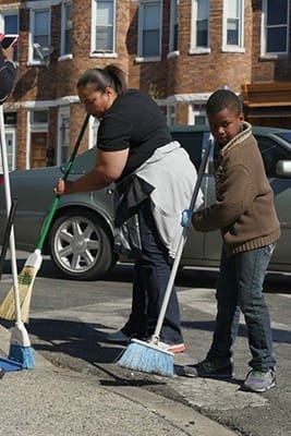 Christy Lewis and a neighborhood youth sweep broken glass and debris outside a looted store in West Baltimore April 28. Maryland Gov. Larry Hogan declared a state of emergency and activated the National Guard to address the violence that erupted in response to the unexplained death of a 25-year-old black man while in police custody. CNS photo/Olivia Obineme, Catholic Review 
