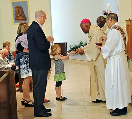 Six-year-old Lauren Schroeder presents the gifts to Archbishop Wilton D. Gregory. She is accompanied by her mother, Meaghan, her siblings and her uncle, Scott Williamson. Photo By Lee Depkin