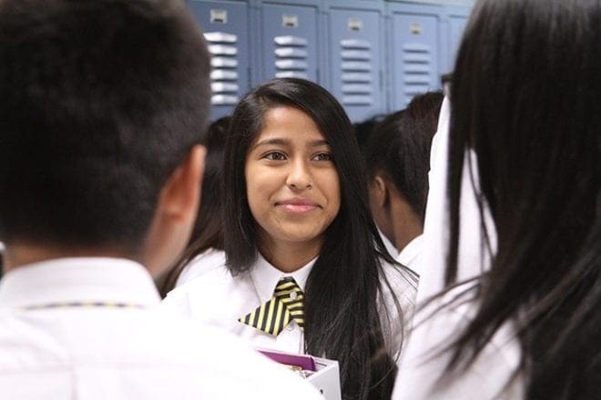 Bethy Ramirez-Sanchez briefly interacts with fellow students before they go to their second period class. She was one of two students profiled during the inaugural school year at Cristo Rey Atlanta Jesuit High School. Photo By Michael Alexander