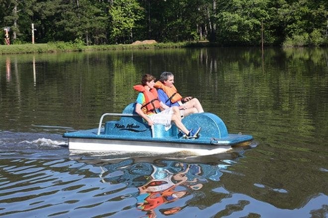 Toni’s Camp volunteer Michael Miller, left, and camper Willy Watkins take a ride on the lake in a pedal boat, May 2. Photo By Michael Alexander