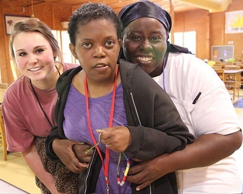 (R-l) Nicole Manning, her younger sister Keke, and Keke’s camp volunteer escort Maddy Reyhan pose for a photo after lunch. Nicole, who also serves as a volunteer, has been bringing Keke to Toni’s Camp for 32 years. Photo By Michael Alexander