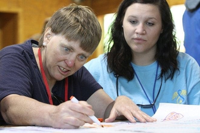 Kathy Jablonski, left, of St. Jude the Apostle Church, Sandy Springs, works with other campers on a poster for her cabin. Laura Orf, right, spent the weekend before her May 9 graduation from Valdosta State University volunteering at Toni’s Camp. After graduation Orf will be a special education teacher for an elementary school in Fulton County. Photo By Michael Alexander