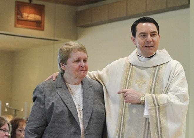 Father Christopher Monturo, right, pastor of St. Anthony of Padua Church, West Harrison, N.Y., presents Grey Nun of the Sacred Heart Sister Dawn Gear to the congregation and student body as a person to model one’s Christian life after. Father Monturo, the main celebrant for the May 7 Mass marking the 50th jubilee of Sister Dawn, worked for her when he helped clean up St. John Neumann Regional School, Lilburn, as a youngster. Photo By Michael Alexander