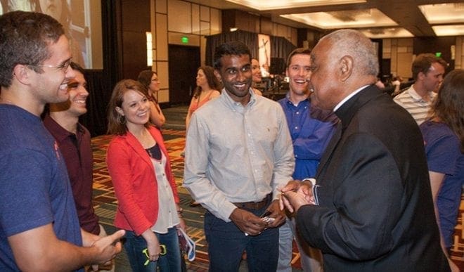 Archbishop Wilton D. Gregory visits with Georgia Tech students volunteering at the Summum Vado booth Friday night, June 5, at the "Revive" track. 2015 was the 20th anniversary of the Eucharistic Congress, held annually in the Archdiocese of Atlanta at the Georgia International Convention Center in College Park. Photo by Thomas Spink