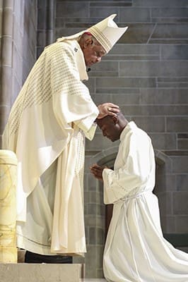Archbishop Wilton D. Gregory conducts the laying on of hands over Valery Akoh during the May 30 rite of ordination to the transitional diaconate. Rev. Mr. Akoh had three years of formation at a seminary in Cameroon, his native country, before coming to the United States in 2011. Photo By Michael Alexander