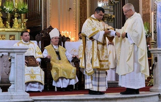Auxiliary Bishop Luis R. Zarama, seated center, looks on as Rev. Mr. Gerardo Ceballos is vested by Msgr. Al Jowdy, pastor of Immaculate Heart of Mary Church in Atlanta. Bishop Zarama ordained Rev. Mr. Ceballos to the transitional diaconate May 23 at the Metropolitan Cathedral in Morelia, Mexico.