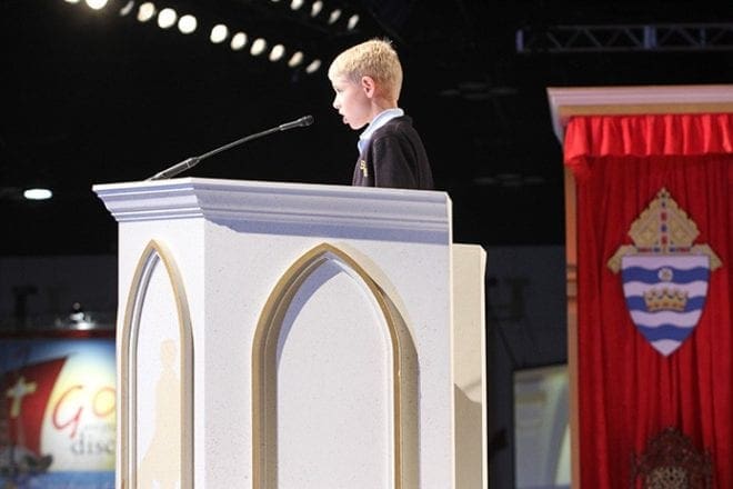 Rising St. John the Evangelist School fifth-grader Luke Patterson proclaims the first reading from the Book of Tobit during the June 5 opening Mass of the Eucharistic Congress. Photo By Michael Alexander