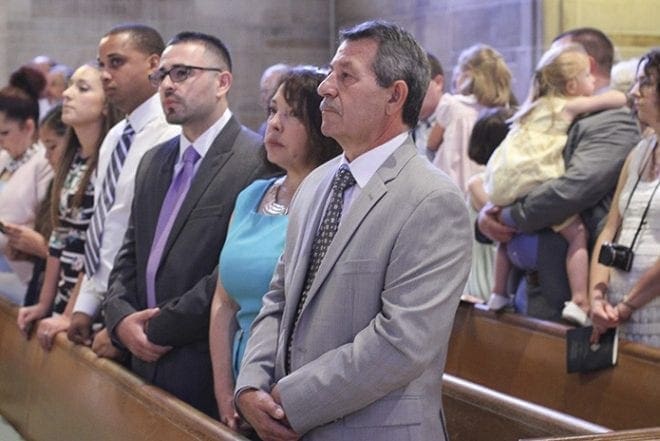 Like all the proud parents, relatives and friends on hand to witness the rite of ordination (foreground to background), Martin and Bertha Carranza of Calhoun, Jorge’s parents, his younger brother Ivan from Acworth and his brother-in-law Victor Rivera watch the opening procession of clergy to the altar. Photo By Michael Alexander