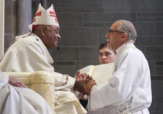 Mark Thomas, right, makes a promise of obedience to Archbishop Wilton D. Gregory, left, and his successors. Photo By Michael Alexander