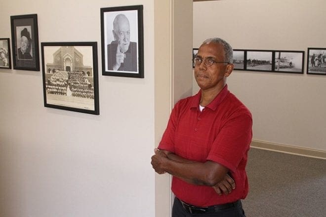 Douglas Watson, executive director of St. Jude Interpretive Center and Garden in Montgomery, Ala., stands inside the center July 31 beside a photo of City of St. Jude founding pastor, Father Harold Purcell. The City of St. Jude is a Catholic, nonprofit organization dedicated to the spiritual, health, social and educational needs of all people, regardless of their religious affiliation, sex, race or national origin. CNS photo/Michael Alexander, Georgia Bulletin 