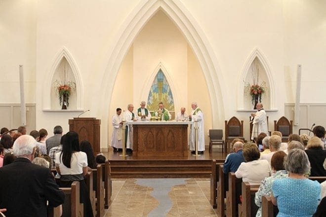 Bishop Luis Zarama, the homilist and main celebrant for the Mass of dedication, holds the body of Christ before the congregation during the Lamb of God. Photo By Michael Alexander