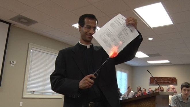 Father Neil Dhabliwala, pastor of St. Luke the Evangelist Church in Dahlonega, burns the mortgage on the parish hall built in 2008 at a special celebratory dinner Aug. 15. Through a capital campaign, led by parishioners, the parish was able to retire the debt of $750,000 ahead of schedule. Photo By Allen Kinzly