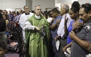 Seguido por el dicono y maestro de ceremonias Joe Pupo de St. Thomas Aquinas Church en Alpharetta, el Obispo Luis Zarama camina bendiciendo con agua bendita a la congregacin. Foto de Michael Alexander