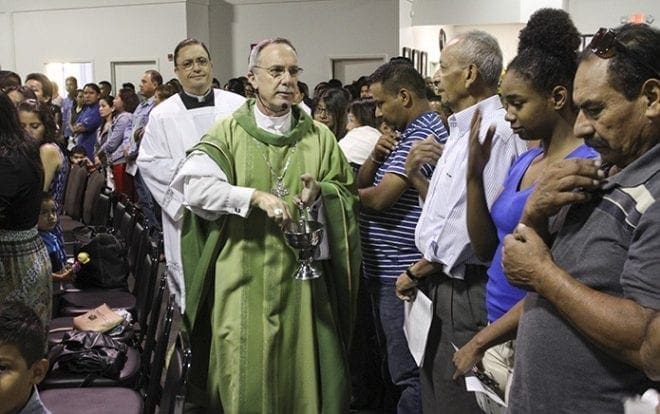 Followed by master of ceremonies Deacon Joe Pupo of St. Thomas Aquinas Church, Alpharetta, Bishop Luis Zarama walks through the congregation blessing them with holy water. Photo By Michael Alexander