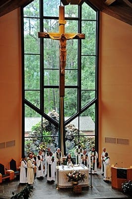 Former and current priests and deacons of St. Philip Benizi Church, Jonesboro, gather around the altar, in front of the striking window and crucifix, during the 50th anniversary of the first Mass Sept. 12. Photo By Lee Depkin