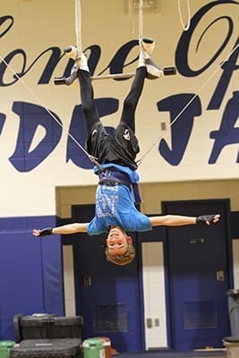 Seventh–grader Evan Sitzmann hangs upside down from the swinging trapeze during a Sept. 16 rehearsal. Photo By Michael Alexander
