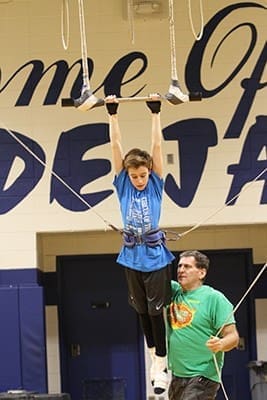 Circus of the Kids founder Bruce Pheffer, right, gives Evan Sitzmann a shove from behind to start his forward momentum on the swinging trapeze. Photo By Michael Alexander