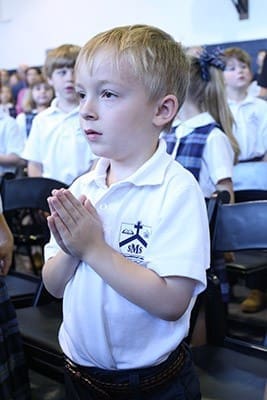 Eli Jones, a kindergarten student at St. Mary’s School, Rome, stands with his hands folded during the beginning of the school’s 70th anniversary Mass Sept. 1. Photo By Michael Alexander