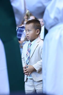 Standing on the front row with fellow classmates, 4-year-old prekindergarten student Dyllan Nguyen is dapper in a khaki suit and plaid tie for the Sept. 1 school anniversary Mass. Photo By Michael Alexander