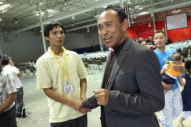 Bishop Lucius Hrekung, right, of the Diocese of Hakha in Burma, greets John Cheng, 35, of St. Louis, Mo., and a host of others as he departs the North Atlanta Trade Center, Norcross, site of the sixth annual gathering of the National Conference of Burmese Catholics. Photo By Michael Alexander