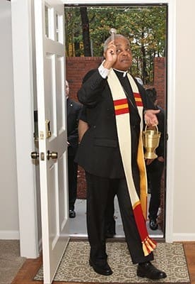 Archbishop Wilton D. Gregory sprinkles holy water in the foyer of one of the four units that make up the St. Charles Borromeo House, Atlanta. Photo By Michael Alexander