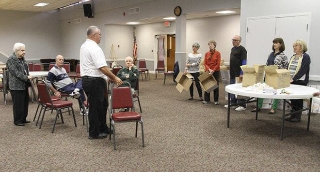 Bob Spidel, third from the left, gives some instructions to the group before they actually start packing care boxes for the troops. Spidel and Eleanor Camarata, far left, head up Holy Cross Church’s Troop Support Ministry, which began in October 2008. Photo By Michael Alexander