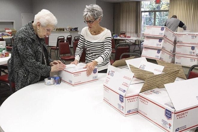 Eleanor Camarata, left, and Barbara Kerner tape the boxes shut once the packing crew has filled them. Photo By Michael Alexander