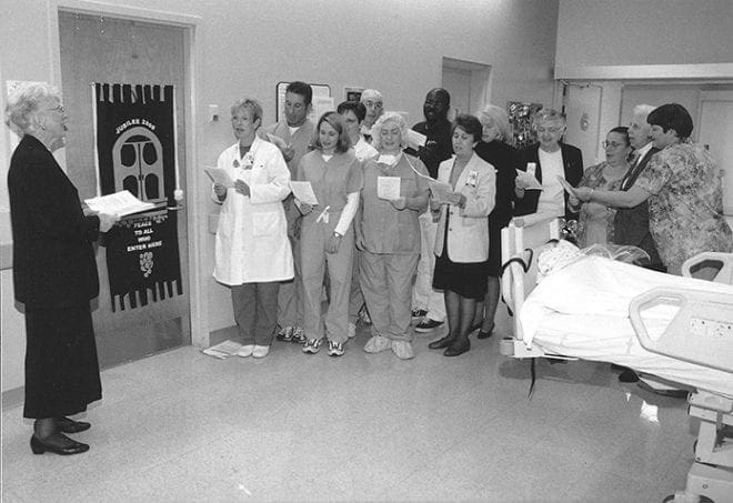 In this Oct. 2000 photo during Pastoral Care Week, Sister of Mercy Valentina Sheridan, far left, director of Pastoral Care at Saint Joseph’s Hospital, leads the post anesthesia care unit staff and chaplains in singing “Peace Is Flowing Like A River.” With the Jubilee Year banner in tow, each week the Pastoral Care staff visited a different department during that Jubilee Year of 2000. Photo By Michael Alexander