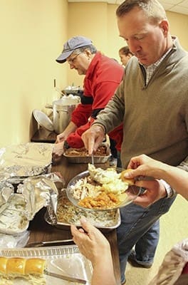 Jeremy Ransom, foreground right, works on the serving line with at least six or seven other volunteers including (background, l-r) Glenn Tucker and Maggie Clutter. They usually serve anywhere from 100-150 people during the annual Thanksgiving dinner. Photo By Michael Alexander