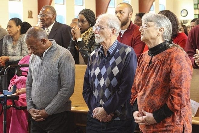 Thoughts and prayers for the people of Paris, France, two days after the horrific terrorist attacks, were on the minds of the congregation attending the Nov. 15 Sunday Mass at Our Lady of Lourdes Church, Atlanta, including (foreground, kneeling l-r) Lionel Alexander and Bill and Mary Moon. The Moons lived in Europe from 1970-1984 and three of their six children were born in France. Photo By Michael Alexander