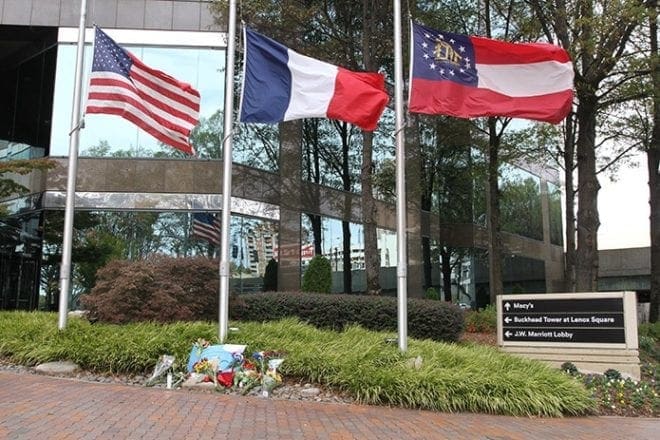 (L-r) The American, French and Georgia state flags blow in the wind at half-mast Nov. 15 as a makeshift memorial is displayed below them, just outside the French Consulate in Atlanta. Photo By Michael Alexander