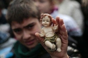 A child in St. Peter's Square holds up a figurine of the baby Jesus as Pope Francis leads the Angelus at the Vatican Dec. 15. Children observed an annual tradition by bringing their Nativity figurines for the pope to bless.