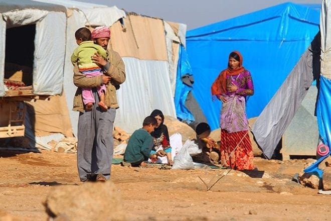Internally displaced Syrians stand outside their tents Nov. 20 at a camp in Idlib, Syria. CNS photo/Ammar Abdullah, Reuters