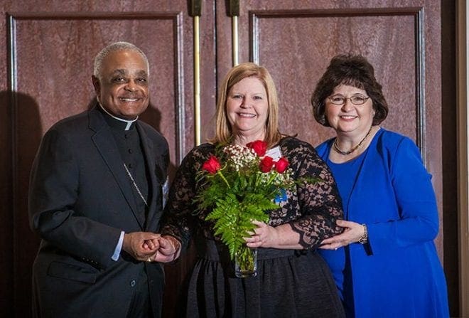 Lisa Cordell, principal of Our Lady of the Assumption School in Atlanta, received the 2015-2016 Principal of the Year award at this year's archdiocesan Catholic education banquet. Presenting the award were Archbishop Wilton D. Gregory, left, and Diane Starkovich, Ph.D., superintendent of Catholic schools, right. Photo by Thomas Spink