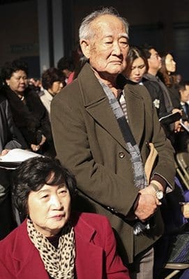 Pak Ginyal, standing, an 88-year-old catechumen from St. Andrew Kim Church, Duluth, is joined by his wife, 75-year-old Agnes Lee, during the presentation of catechumens at the 2016 Rite of Election. St. Andrew Kim has 26 catechumens this year. Photo by Michael Alexander