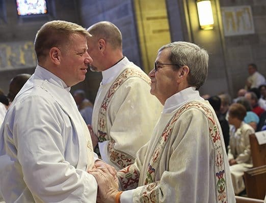 Deacon Nicholas Johnson of Prince of Peace Church, Flowery Branch, left, extends the customary sign of peace to newly ordained deacon James Skolds of St. Oliver Plunkett Church, Snellville. Photo By Michael Alexander