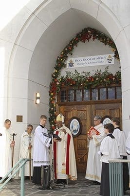 Seminarian Dan Fitzgerald holds the book as Archbishop Wilton D. Gregory faces the congregation and conducts the rite for the opening of the Holy Door of Mercy. Photo By Michael Alexander