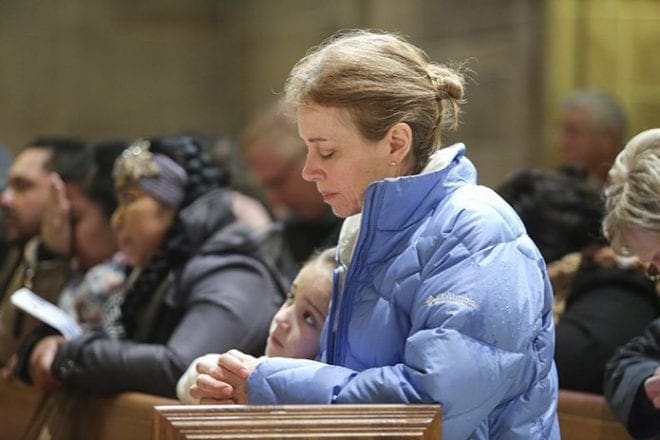 Prior to the Mass for the Unborn, Karen Papania, right center, of St. John Neumann Church, Lilburn, and her 8-year-old daughter, Sophia, join the congregation in praying the sorrowful mysteries of the rosary. Photo By Michael Alexander