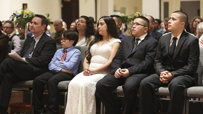 (L-r) Mike Mulqueen, his son Mickey, Laura Garcia and her brothers, Edgar Ortega and Henry Garcia, listen to Father Mark Starr’s Easter Vigil Mass homily. The Garcias, Ortega and Mulqueen were four of the eight new Catholics coming into the Catholic Church March 26 at St. Clare of Assisi Mission, Acworth. Eight-year-old Mickey also received his first holy Communion that night. Photo By Michael Alexander