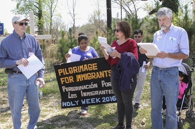 (Foreground, l-r) Immaculate Heart of Mary parishioners Kent Williams, Clara Azcunes and Mark Bracken and the rest of the marchers stop three blocks west of Interstate 85 and pray before proceeding to the church. In the background are Guadalupe Robles and Father Fabio Sotelo of St. Bede’s Episcopal Church, Atlanta. Photo By Michael Alexander