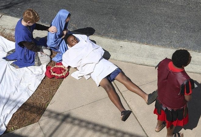 In this representation of the 13th Station of the Cross (Jesus is taken down from the cross), Mary (played by Katie Fish) and Joseph of Arimathea (played by Nathan Brieske) kneel beside the body of Jesus (played by Darryl Cooper). The stations were portrayed by seventh-graders at Immaculate Heart of Mary School, Atlanta. Photo By Michael Alexander