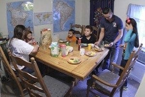 El Refugio overnight guests (l-r) Melissa Sandoval and her granddaughter Hailee eat breakfast along with additional guests Jared Martinez, his brother Jafet, his father Milber, and his sister Brianna. Melissa drove from Rome to visit her husband at the Stewart Detention Center. Milber drove his family down from Queens, N.Y., so his wife Debora could visit her brother. Photo By Michael Alexander