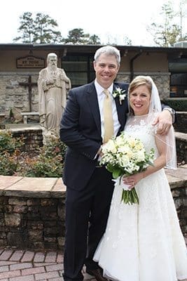 Newlyweds Will and Beth Dempsey stand before the statue of St. Jude the Apostle following their nuptial Mass. It was the idea of St. Jude principal Patty Childs to hold the wedding during a weekday Mass, giving students a firsthand lesson about the sacrament of marriage. Photo By Katy Cowan