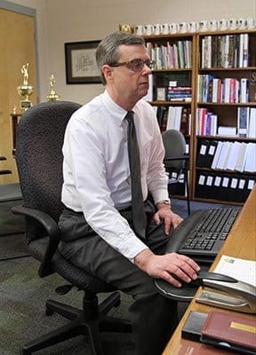 Staring at his computer screen, Blessed Trinity High School principal Frank Moore looks over the morning announcements for April 19 as he prepares to print them. Photo By Michael Alexander